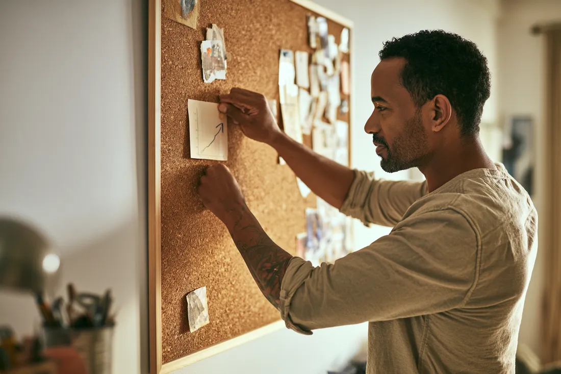 Man pinning steady progress notes to a board, tracking his rebuild — Esketit personal loans